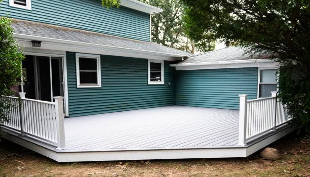 Backyard of a two-story home featuring teal horizontal siding, white-trimmed windows, and a newly installed gray composite deck with white railings.