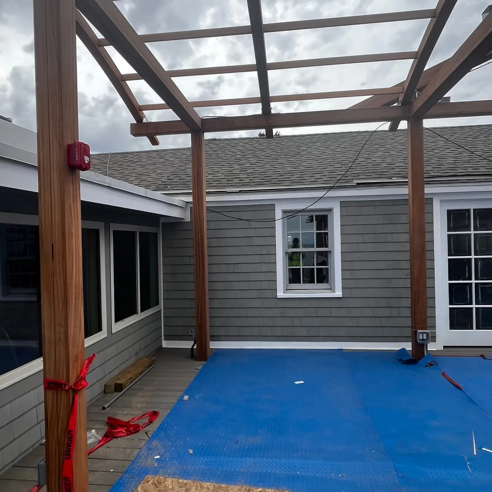 Gray shingle siding and asphalt shingle roof on a commercial building with new timber pergola framing